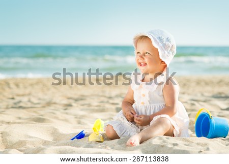Baby playing on the sandy beach near the sea