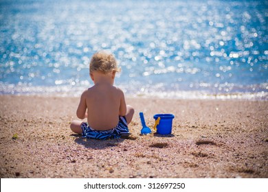 Baby Playing With Sand On Sea Shore