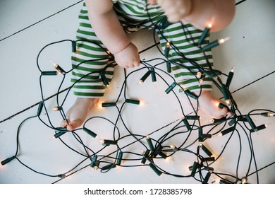 A Baby Playing With Tangled Festive Christmas Fairy Lights