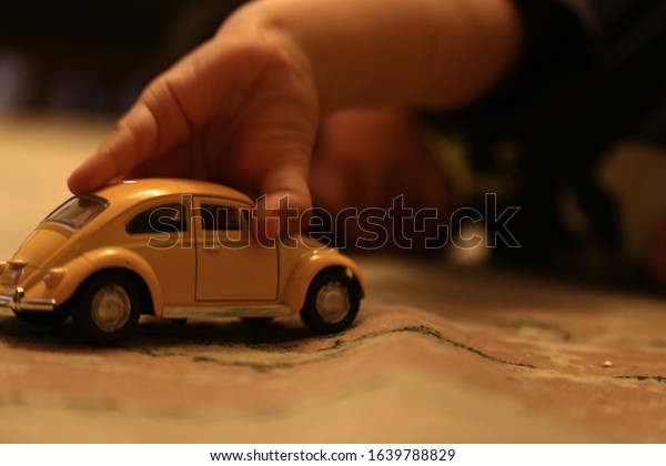 A baby plays with a small\
toy car