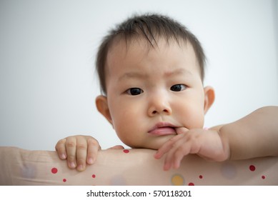 Baby Portrait Laying  In Cot Cradle With Finger In Mouth