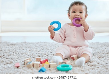 Baby, portrait and playing with toy on floor in home for sensory development, teething progress and biting. Infant, person and silicone ring in mouth for tooth growth, gums satisfaction and chewing - Powered by Shutterstock