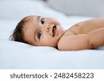 Baby portrait, smile and lying on bed for relax with healthy growth, cute and wellness in home. Infant girl, happy face and rest on mattress for development, youth and diaper change in bedroom