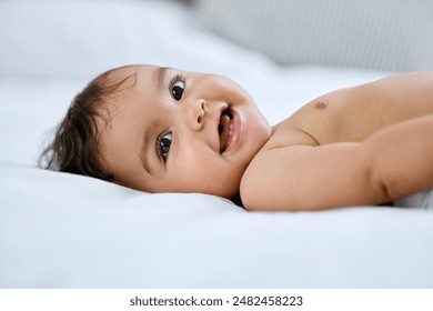 Baby portrait, smile and lying on bed for relax with healthy growth, cute and wellness in home. Infant girl, happy face and rest on mattress for development, youth and diaper change in bedroom