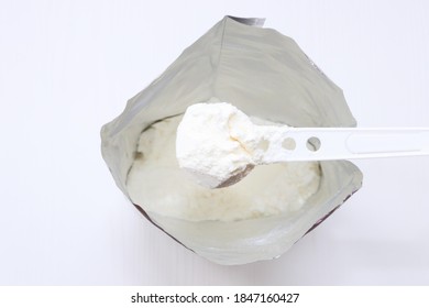 Baby Powder Milk Formula In The Package With A Spoon.  Infant Formula In Spoon And Package On White Background