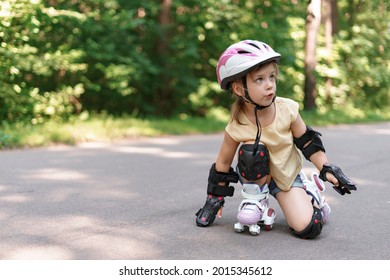 Baby In Protective Sportswear. Little Girl Learning To Roller Skate