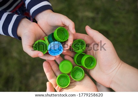 baby puts plastic lids in mother's hands. parent and his child collect cover. recyclable. collecting bottle caps.