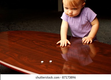 Baby Reaching Across Coffee Table At White Pills