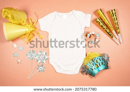 Baby romper onesie bodysuit product mockup. New Year theme SVG craft product mockup styled with party hats and blowers decorations. Gold and blue theme creative composition flatlay.