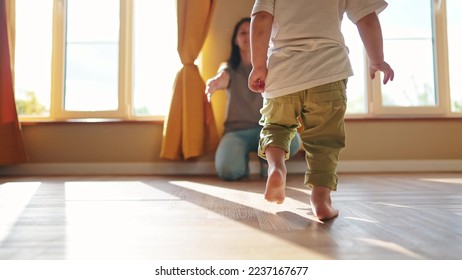 baby runs to mom at home. a child with bare legs runs across the floor to his mother against a sunny window. happy family kid dream concept. kid running back view at home hugging lifestyle mom - Powered by Shutterstock