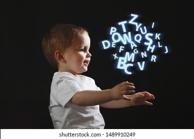 Baby Says, The Concept Of Problems With Dyslexia And Dysgraphia. A Child Learns To Speak, A Boy On A Black Background, A Cloud Of Chaotic Letters On The Right