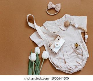 Baby Shower Concept. Newborn Baby Clothing, Tulips And Wooden Toys On Brown Background, Top View, Flat Lay.
