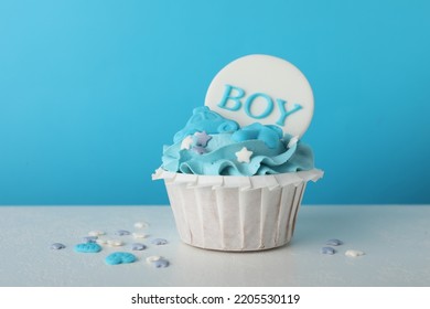 Baby Shower Cupcake With Boy Topper On White Table Against Light Blue Background