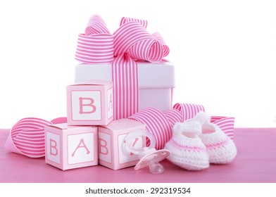 Baby shower Its a Girl pink gift with baby booties, dummy and gift box on pink shabby chic wood table. 