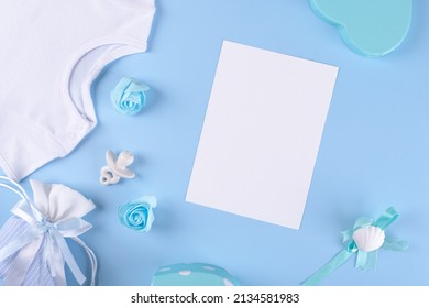 Baby shower invitation 5x7 card mockup with baby boy accessories, bodysuit, nipple or baby's dummy, gift box with copy space on blue pastel color background