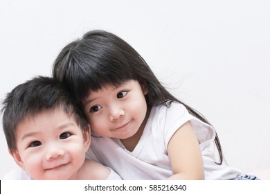 Baby Sister And Brother In White Shirt Hugging Each Other.