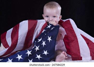 Baby sitting and wrapped by the American flag
