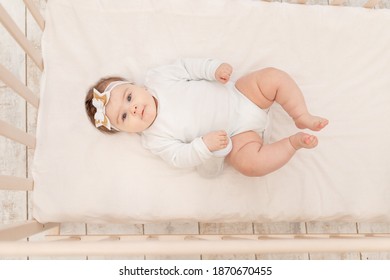 Baby Six Months In Bed With A Bottle Of Water In A White Bodysuit