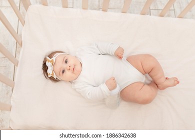 Baby Six Months In Bed With A Bottle Of Water In A White Bodysuit