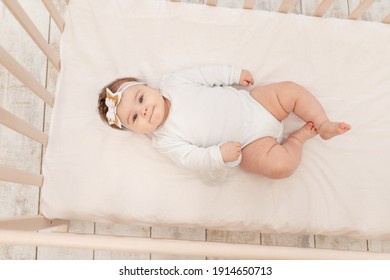 Baby Six Months In Bed With A Bottle Of Water In A White Bodysuit