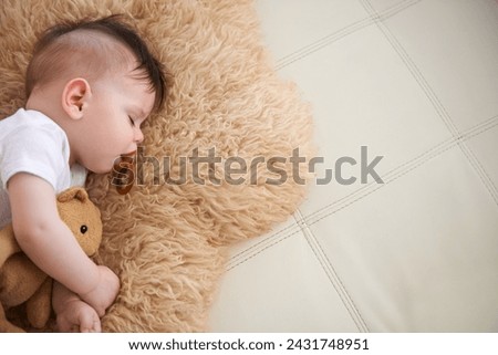 Baby, sleep and cuddle with teddybear on couch at home, rest and relax with dummy and dream. High angle, toddler, and nap in sofa for child development, growth and innocent with peace for bedtime.