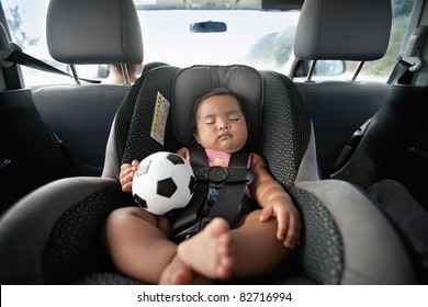 Baby Sleeping In Car Seat And Holding A Soccer Ball