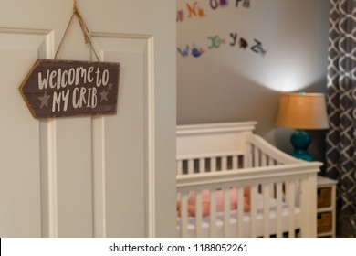 Baby Sleeping In A Crib. The Door To The Nursery Has A Welcome To My Crib Sign.