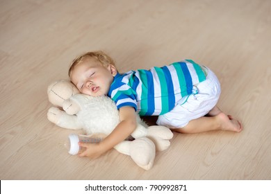 Baby sleeping on wooden floor with stuffed toy sheep and milk bottle. Funny tired little boy falling asleep crawling on hardwood floor at home. Sleepy infant drinking formula on soft cushion.


	
 - Powered by Shutterstock