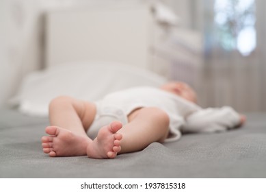 Baby sleeps in bed, view of small baby legs