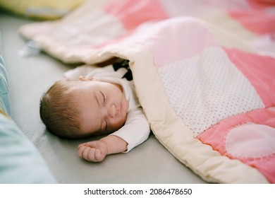 Baby Sleeps On Bed Covered With Pink Patchwork Quilt