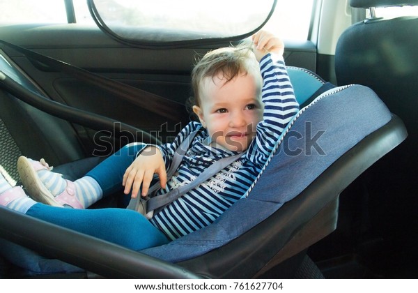 baby smile in a safety car seat.\
Safety and security. one year old child girl in blue wear sit on\
auto cradle. Rules for the Safe Transport of Children.\
Holders.