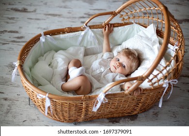 A Baby With Snow-white Hair Sits In An Old Cradle.