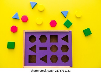 Baby Sorter With Geometric Figures From Wood On A Yellow Isolated Background. Horizontal Photo