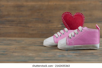 Baby sport shoes on wooden floor. Kid small size  sneakers, canvas booties closeup view. Space, card invitation template