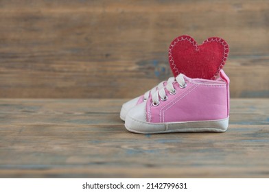 Baby sport shoes on wooden floor. Kid small size  sneakers, canvas booties closeup view. Space, card invitation template