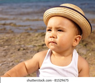 Baby With A Straw Hat In The Beach