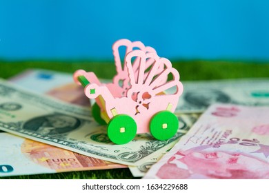 Baby Stroller Stands On Paper Money. Conceptual Photo, Cost Of Maintaining A Child, Expenses For Raising Food, Clothing And Education.