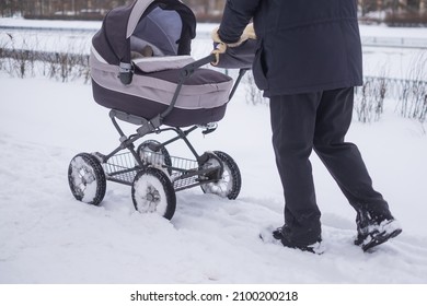 Baby Stroller Wheel On Snowy Road In Winter.