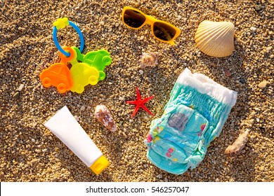 Baby summer necessities lying  on top of sand beach. 