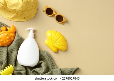 Baby Sun Safety Concept. Sunscreen Cream Bottle, Sun Glasses, Sand Molds, Towel, Panama Hat On Beige Table. Flat Lay, Top View.