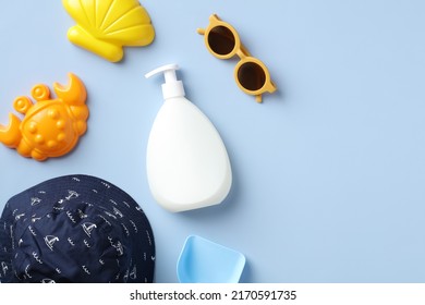 Baby Sunscreen Bottle Mockup, Sunglasses, Panama Hat, Sand Molds On Blue Background. Summer Vacation Concept.