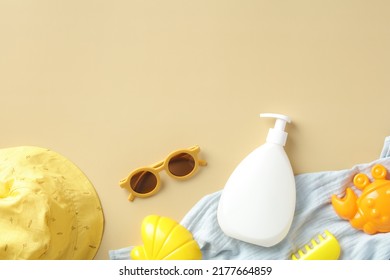 Baby Sunscreen Cream Bottle With Sunglasses, Panama Hat, Towel, Sand Molds On Beige Table. Sun Safety Concept.