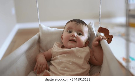 baby is swinging on swing. baby blonde play at home sits on a rope swing. happy family kid dream kindergarten concept. pov view of baby playing in baby swing indoors lifestyle - Powered by Shutterstock