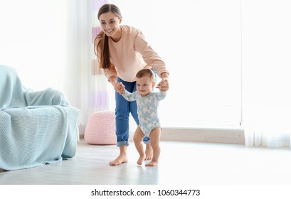 Baby Taking First Steps With Mother's Help At Home