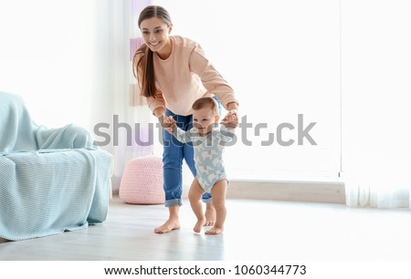 Baby taking first steps with mother's help at home