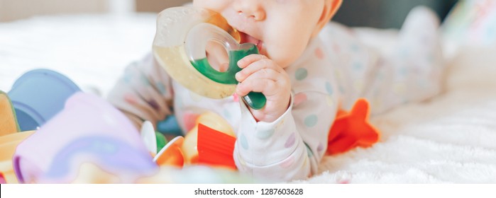 Baby Teether, Kid Bite Teething Toy In Mouth, Infant Child Growing First Tooth, Little Boy Or Girl Crawling On Bed At Home