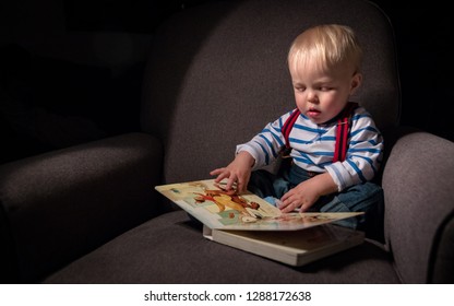 Baby Toddler Enjoys Reading A Childrens Book In Big Soft Comfy Chair.