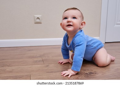 Baby Toddler Is Near The Electrical Outlet On The Home Wall. Danger And Protection Of Child Fingers From Electric Shock, Aged 6-11 Months