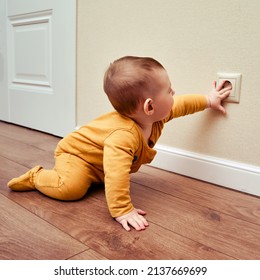 Baby toddler reaches into the electrical outlet on the home wall with his hand. Danger and protection of child fingers from electric shock, aged 6-11 months - Shutterstock ID 2137669699
