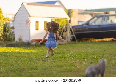 Baby Toddler Running On Green Lawn Near The House.